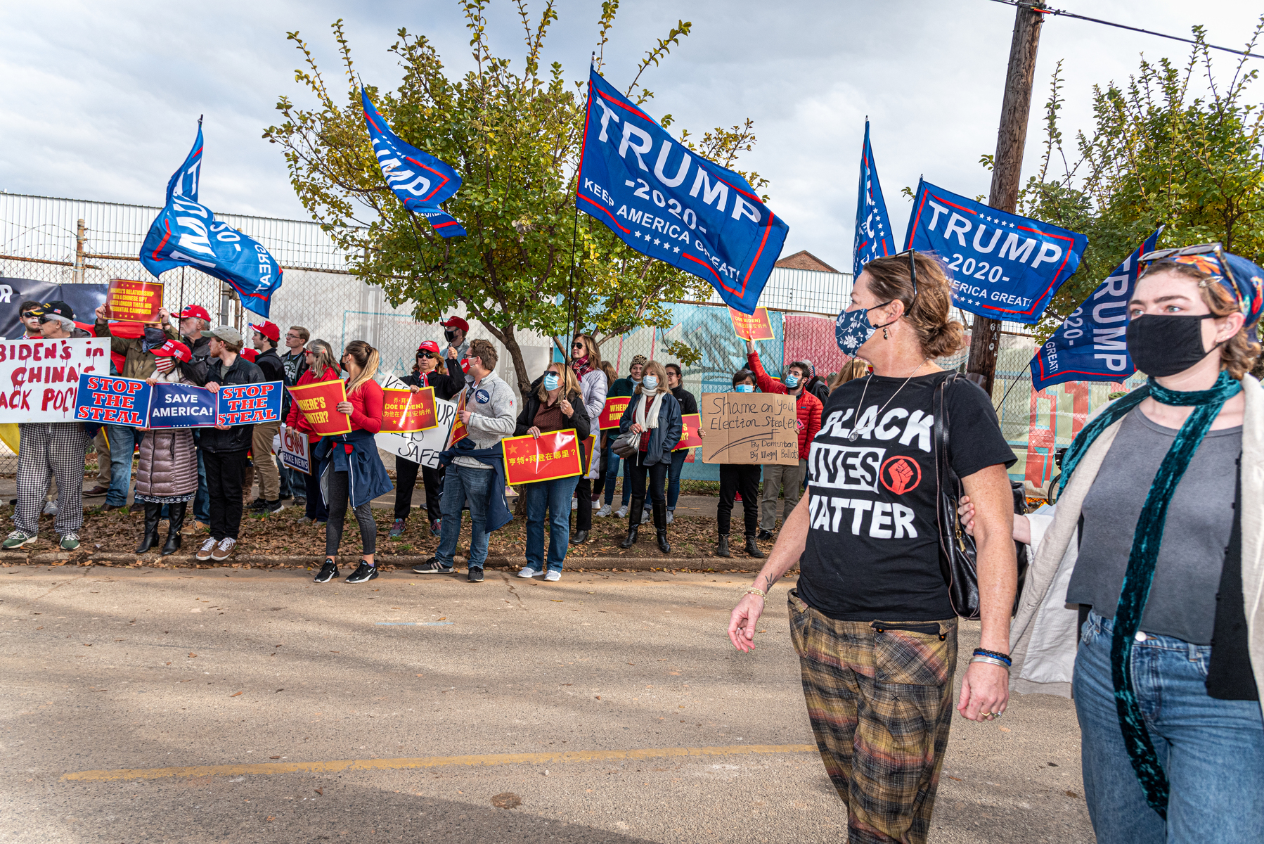 December 15, 2020 - Atlanta, GA. Two women walk past pro-Trump demonstrators at a drive-in rally for Georgia Democratic U.S. Senate candidates Jon Ossoff and Raphael Warnock.